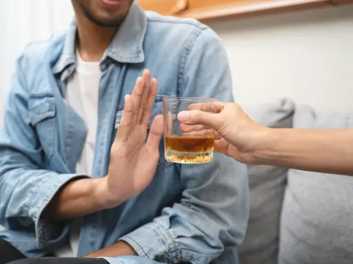 Mężczyzna odmawia alkoholu, symbolizując dobrowolne leczenie odwykowe i nowy początek.