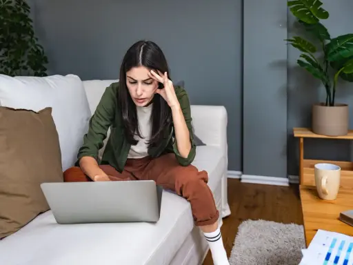 Introwertyczka skupiona na pracy przy laptopie na kanapie. Idealna praca dla introwertyka, gdzie można pracować w spokoju.