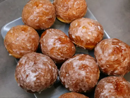 Puszyste pączki z piekarnika, oblane lukrem, kuszą swoim wyglądem. Idealne na tłusty czwartek lub jako słodka przekąska.