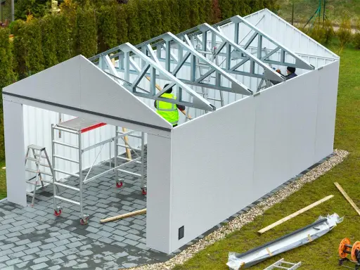 Budowa garażu w toku. Pracownicy montują konstrukcję dachu. Może to być kara za postawienie blaszaka bez zgłoszenia, jeśli nielegalnie.