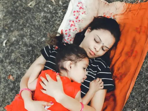 Mama i dziecko leżą przytuleni, uosabiając sztukę prostego życia. Ich spokój i bliskość to najpiękniejszy obraz.