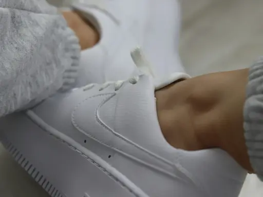 Białe sneakersy z szarym swetrem. Dowiedz się, jak zabezpieczyć białe buty, by długo wyglądały jak nowe.