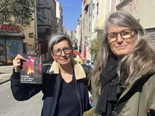 Deux femmes, l'une tenant un livre, dans une rue de Marseille. Le visage de madone de l'une d'elles est encadré par des lunettes.