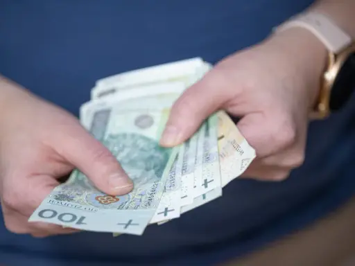 Dłonie trzymające polskie banknoty 100 zł. Czy to nagroda, czy może podatek od nagrody?