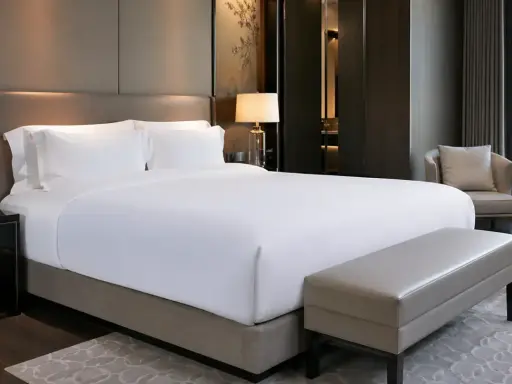 Cama de hotel con sábanas blancas impecables. ¿De qué marca son los colchones de los hoteles? Este lujoso dormitorio invita al descanso.