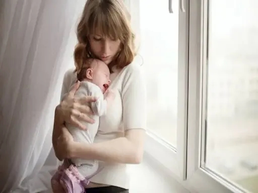 Zmęczona mama tuli płaczące dziecko, które właśnie robi kupę w nocy.
