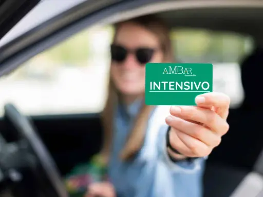 Mujer con gafas de sol muestra tarjeta "INTENSIVO" de autoescuela. Obtener el carnet B+E es difícil, pero este curso intensivo puede ayudar.