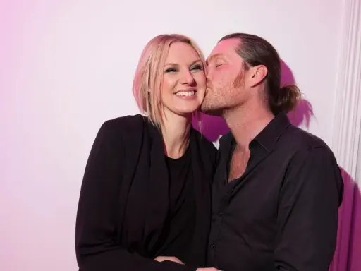 Sanna Nielsen ler när en man med hästsvans ger henne en puss på kinden.