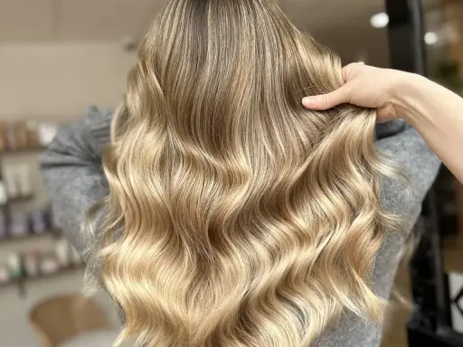 Une chevelure ondulée aux reflets dorés, un blond subtil qui joue avec la lumière.