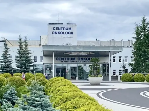 Budynek Centrum Onkologii w Bydgoszczy z zielenią przed wejściem.