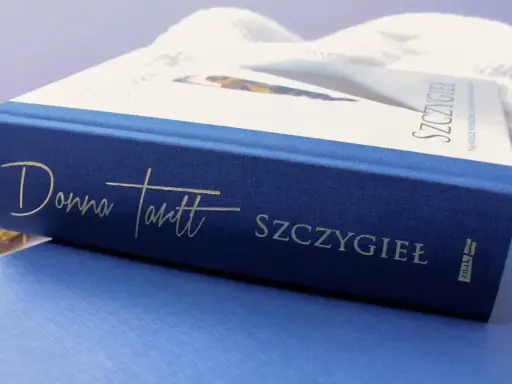 Granatowa okładka książki "Szczygieł" Donny Tartt z wytłoczonym złotym napisem.