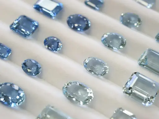 Collezione di acquamarine con taglio smeraldo e altre forme, che brillano su un morbido sfondo bianco.