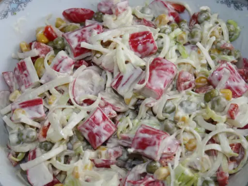 Pyszna sałatka z paluszkami surimi, groszkiem, kukurydzą i porem, polana kremowym sosem.