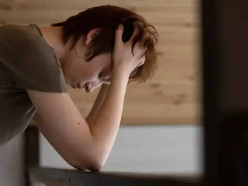 En person med händerna i håret, ser nedåt. Kanske en bild som visar hur man kan tänka kring hur minskar man stress.