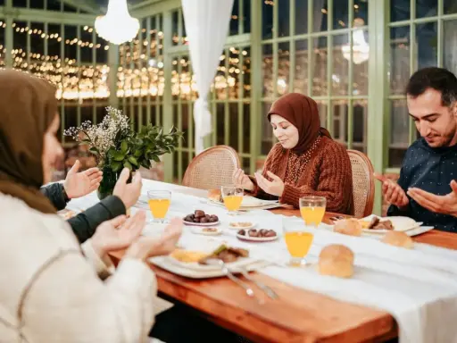 Familie betet vor dem Iftar. Sie fragen sich, was sagt man wenn man fasten will, bevor sie essen.