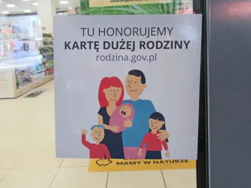 Plakat informujący o honorowaniu Karty Dużej Rodziny z rysunkiem rodziny.