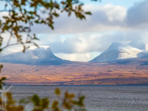 Vacker vy över Lapporten i Abisko, Sverige. Snöklädda berg reser sig över en höstfärgad tundra vid en sjö.