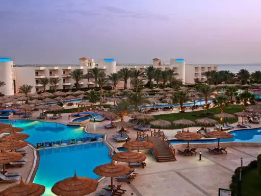 Luksusowy long beach resort Hurghada z basenami, palmami i widokiem na morze.
