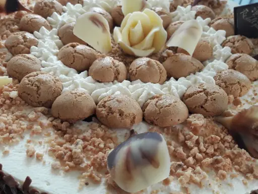 Torta decorata con biscotti, panna montata, cioccolato bianco a forma di rosa e granella. Il re del gelato trama, un capolavoro da gustare.