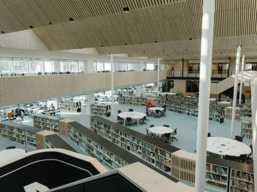 Storslagen biblioteksmiljö med bokhyllor, läsplatser och en modern arkitektur. Här kan man hitta aaltos recensioner bland tusentals böcker.