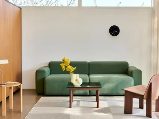 Grünes Sofa, Holztisch, Vase mit gelben Blumen und ein Stuhl im skandinavischen Einrichtungsstil.