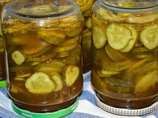 Słoiki pełne plasterków ogórków w zalewie z przyprawami, gotowe do podania jako dodatek do dań. Te ogórki w curry to smak lata zamknięty w słoiku.