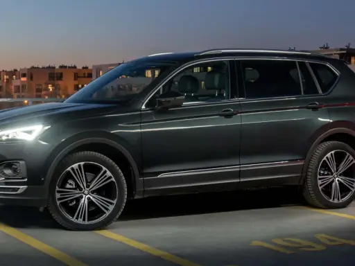 Ciemnozielony SUV, jeden z najbardziej polecanych samochodów 7-osobowych, zaparkowany na dachu parkingu nocą.