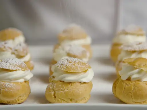 Petits choux garnis de crème fouettée, saupoudrés de sucre glace. La recette parfaite pour un dessert digne du Meilleur Pâtissier.