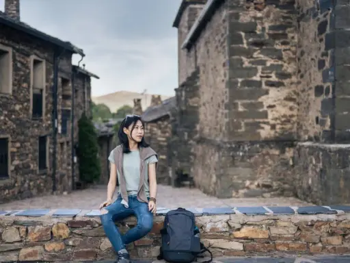 Junge Frau sitzt auf Steinmauer in historischem Dorf in Guadalajara, Spanien.