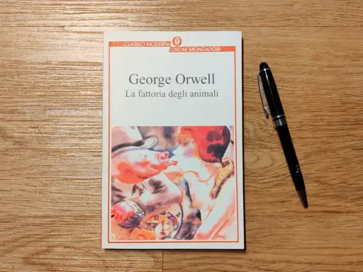 Copertina del libro "La fattoria degli animali" di George Orwell, con una penna nera appoggiata accanto.