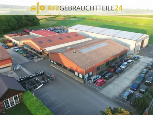 Luftaufnahme eines Autoteile-Lagers mit Gebäuden und vielen Autos.