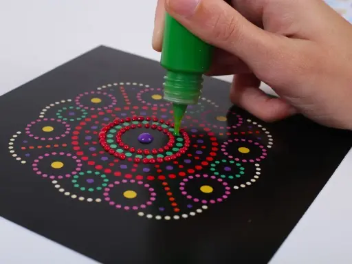 Ręka tworzy kolorowy wzór mandali, co jest formą arteterapii dla seniorów.