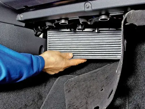 Wymiana filtra kabinowego Skoda Octavia 2. Dłoń wyjmuje filtr z obudowy pod deską rozdzielczą.