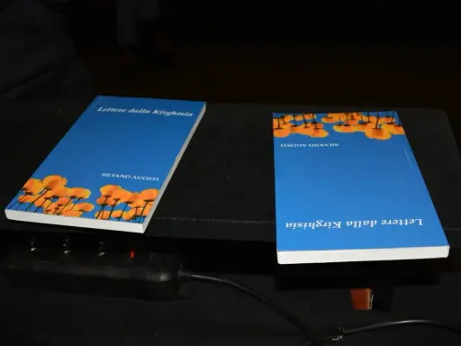 Due libri "Lettere dalla Kirghisia" di Silvano Agosti, con copertina blu e fiori arancioni.