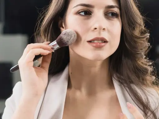 Donna applica il trucco con un pennello, creando un look make up naturale e luminoso.