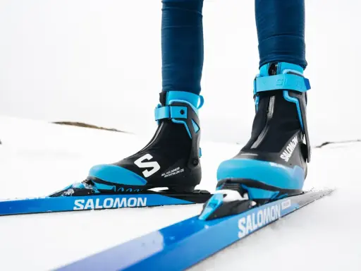 Nära bild på ett par skidpjäxor och skidor i klassisk stil, redo för en tur i snön.