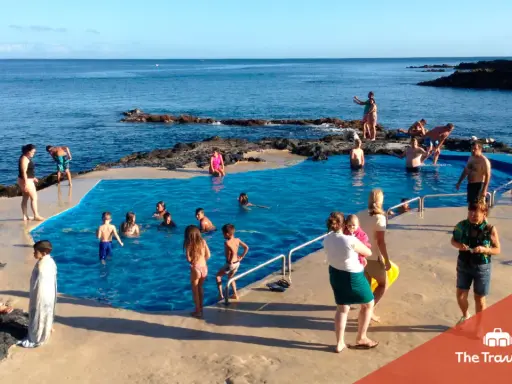 Famiglia felice alle Azzorre con bambini che nuotano in una piscina naturale.