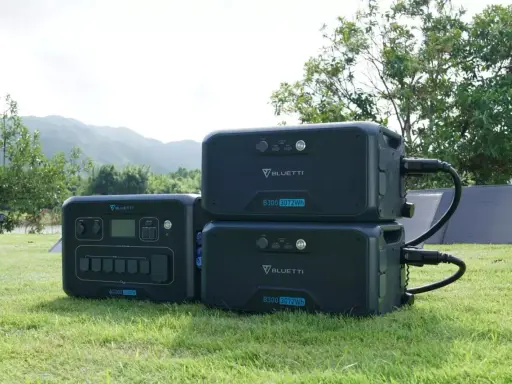 Tre Bluetti-kraftverk, ett AC300 och två B300, står på gräset. De är redo att ge både ac eller dc-ström utomhus.