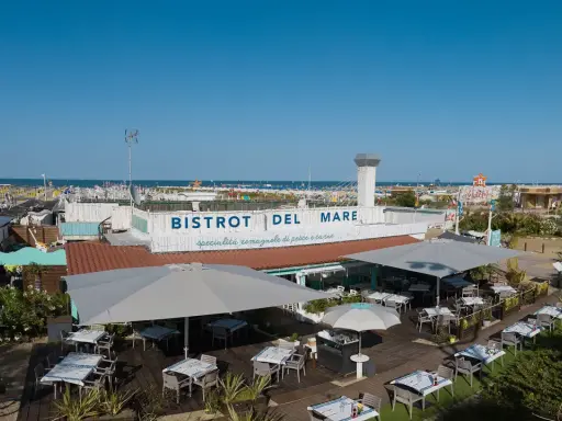 Il Bistrot del Mare a Rimini, con tavoli all'aperto e vista sulla spiaggia affollata, offre specialità romagnole.