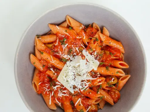 Penne w sosie pomidorowym z ziołami i parmezanem. Idealny przepis na zdrowy makaron, który zachwyci smakiem.