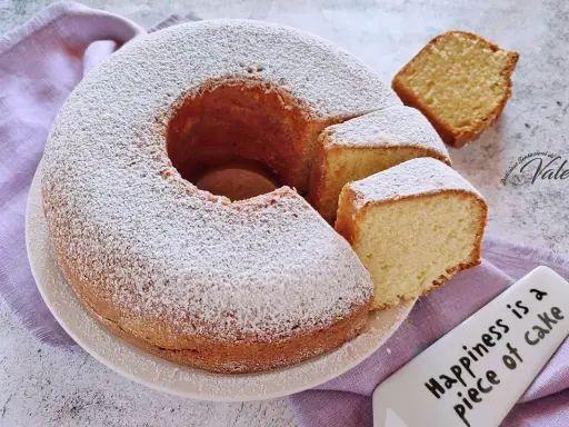 Un ciambellone soffice come una nuvola, cosparso di zucchero a velo, con fette tagliate pronte da gustare.