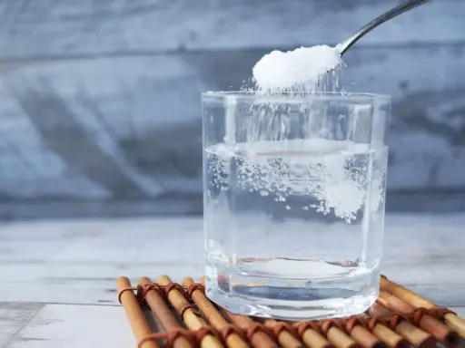 Salz und Zucker werden in ein Glas Wasser gegeben, um Elektrolyte selber machen.
