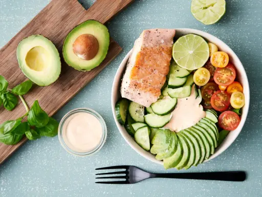 En hälsosam keto recept-bowl med lax, avokado, gurka, tomater och en krämig dressing.
