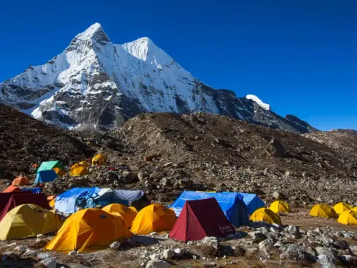 Obóz pod majestatycznym szczytem Karakorum. Kolorowe namioty rozstawione na kamienistym zboczu, gotowe na przyjęcie alpinistów.