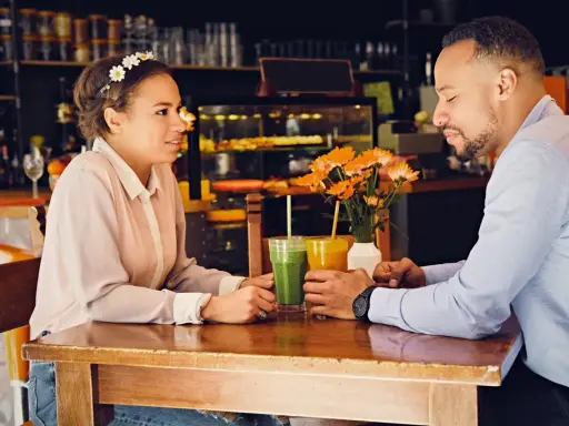 Para, która rozmawia przy stoliku, pijąc soki. W tle kawiarnia. Psychologia mężczyzny miłość w spojrzeniu.