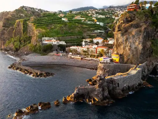 Ponta do Sol, Madeira: malerische Küstenstadt mit terrassierten Bananenplantagen, einem Kiesstrand und einer beeindruckenden Felsformation mit einem steinernen Aussichtsweg.