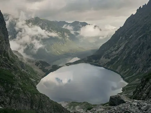 Widok na Morskie Oko, droga na Rysy w oddali. Mgła otula szczyty, odbijając się w tafli jeziora.