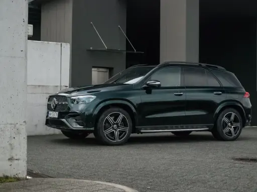 Ciemnozielony Mercedes GLE AMG stoi przed nowoczesnym budynkiem.