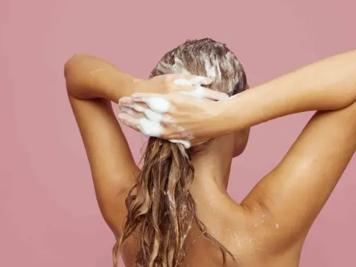 Frau wäscht sich die Haare mit Schaum. Ein Hauch von Friseur Puder für Volumen.