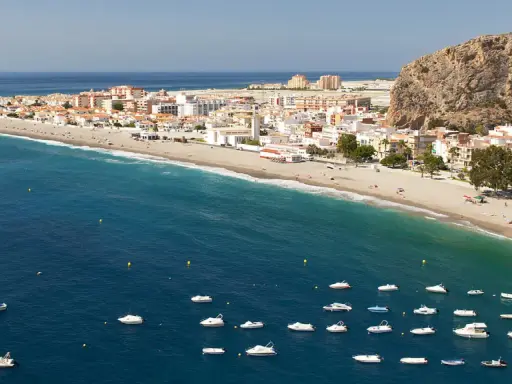 Traumhafte Küstenlandschaft an der Costa Tropical mit weißem Sandstrand, türkisfarbenem Meer und vielen kleinen Booten.
